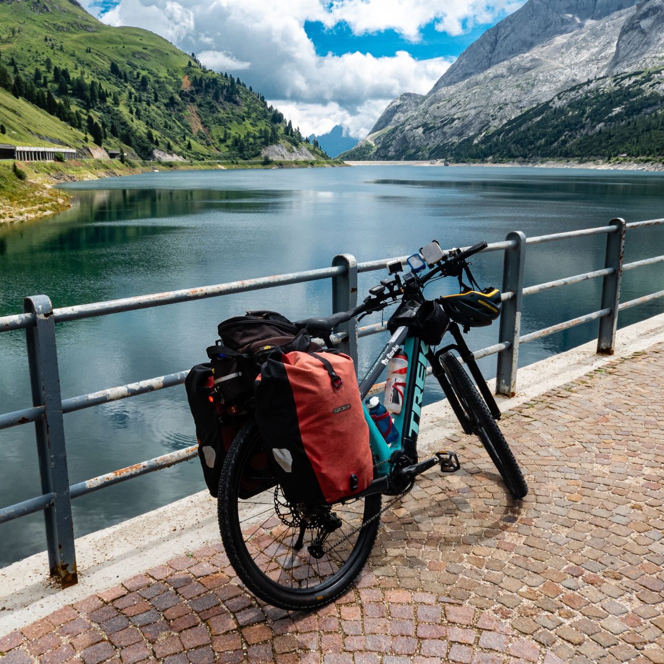 Portage Bagages randonnée à vélo avec VTC-Haute-Savoie Vélo avec sacoches près d'un lac et montagnes sous un ciel partiellement nuageux.